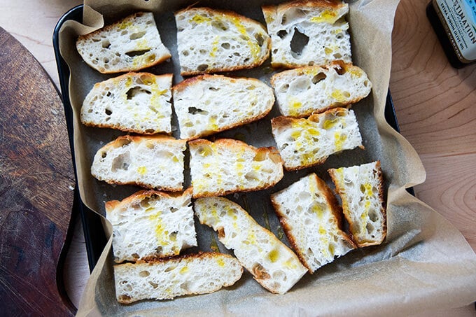 Sliced focaccia on a sheet pan drizzled with olive oil.