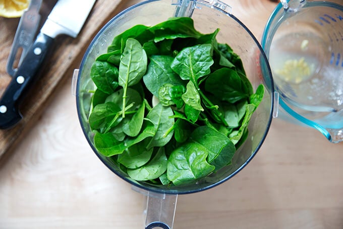 An overhead shot of a food processor holding spinach.