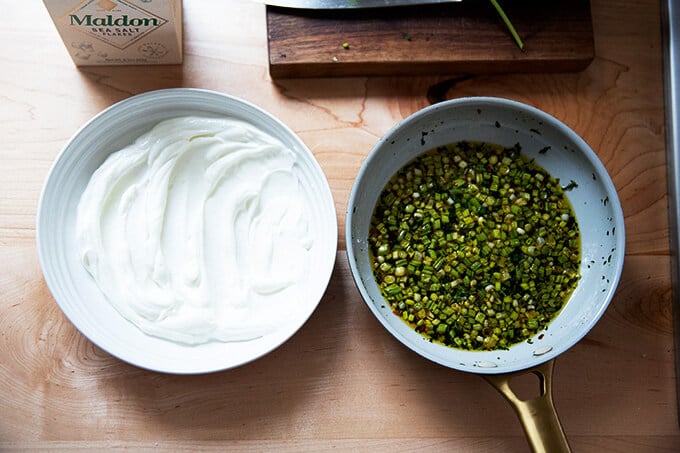 A bowl of yogurt aside a skillet of spicy, sizzling, chile-scallion oil. 