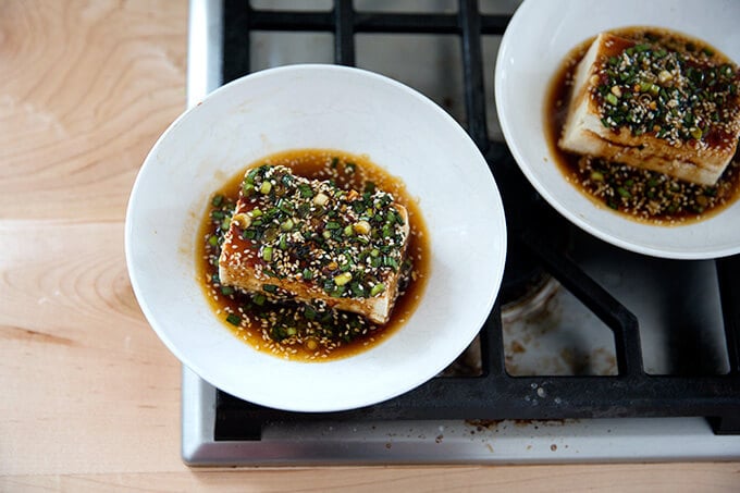 Two bowls of warm tofu topped with sesame-scallion sauce.