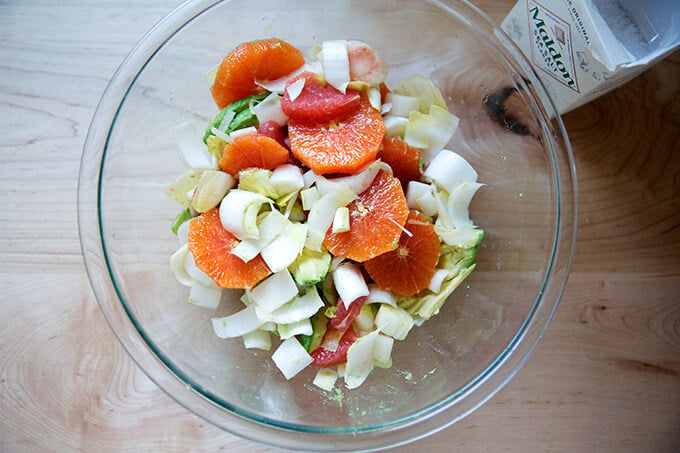 Citrus, avocado, endive in a bowl, seasoned with sea salt.