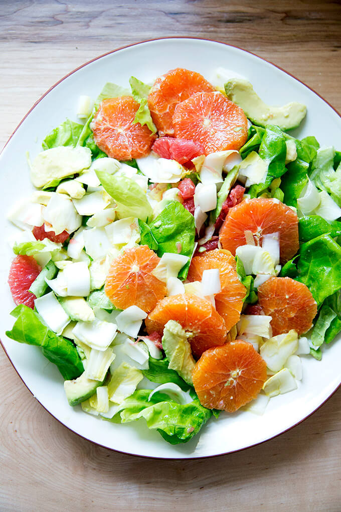 A platter topped with an endive, grapefruit and avocado salad.