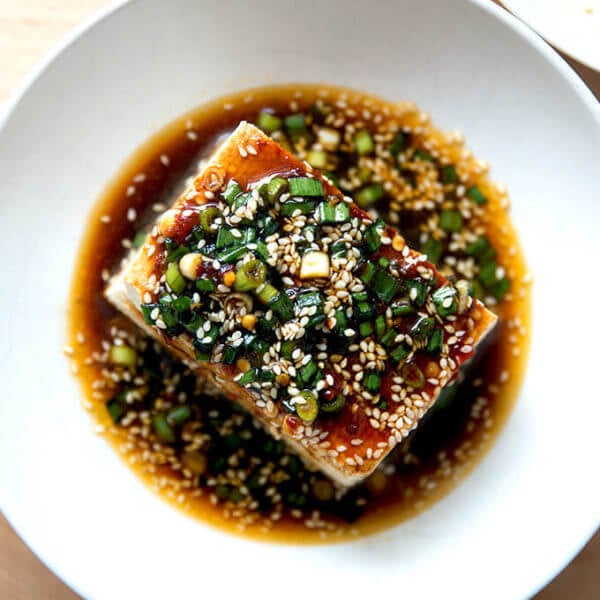 A bowl of warm tofu topped with sesame scallion sauce.