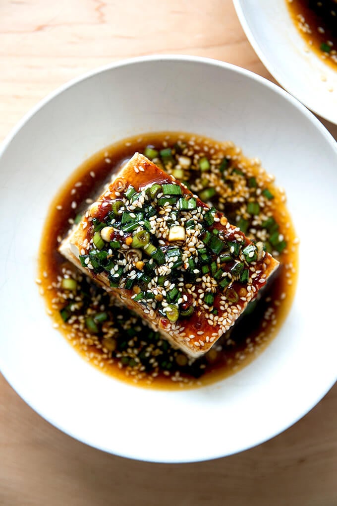 A bowl of warm tofu topped with sesame scallion sauce.