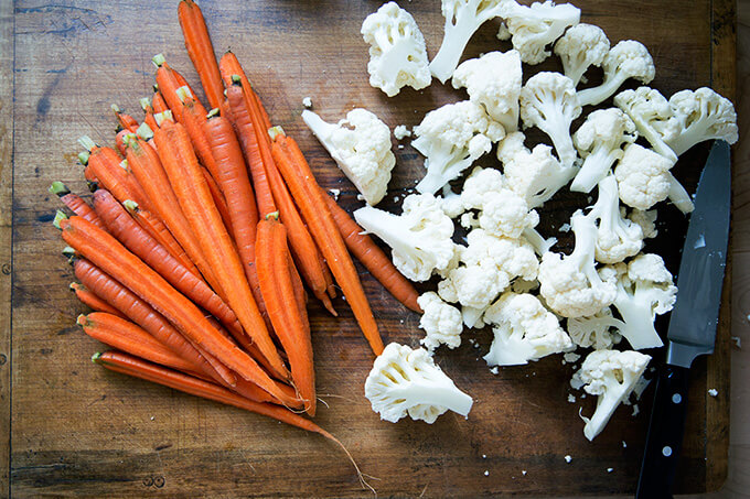 A board with halved carrots and cauliflower florets.
