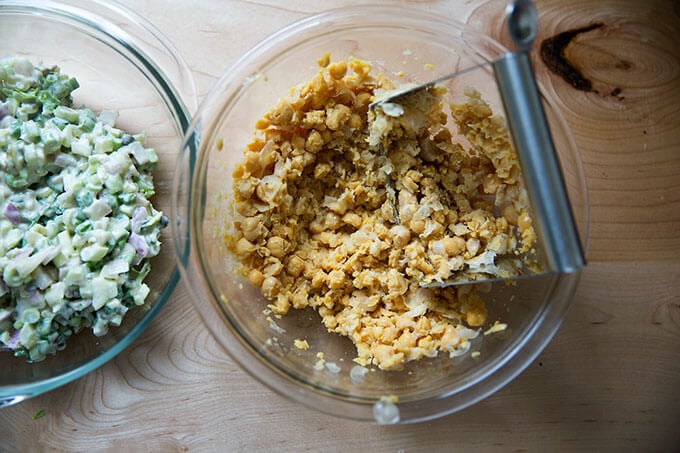 A bowl filled with chickpeas and pastry cutter to mash them up.