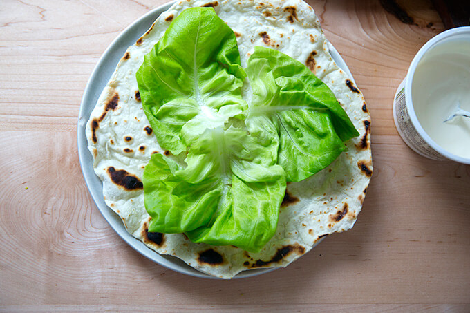Overhead shot of a homemade flour tortilla topped with Boston lettuce.
