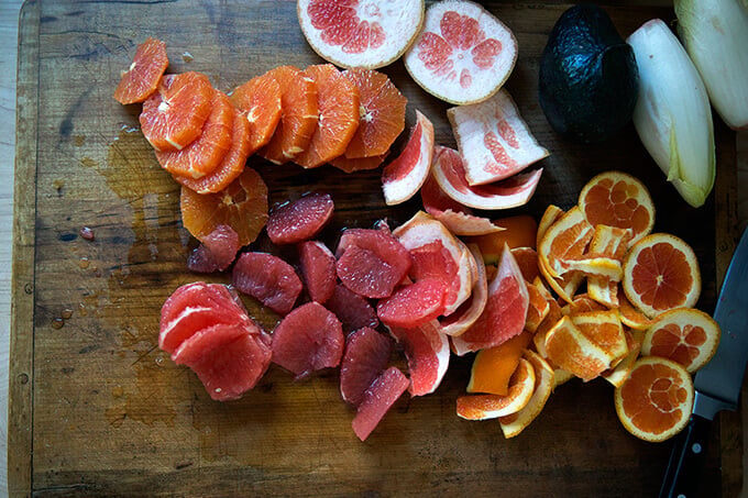 Peeled oranges and grapefruits on a cutting board.