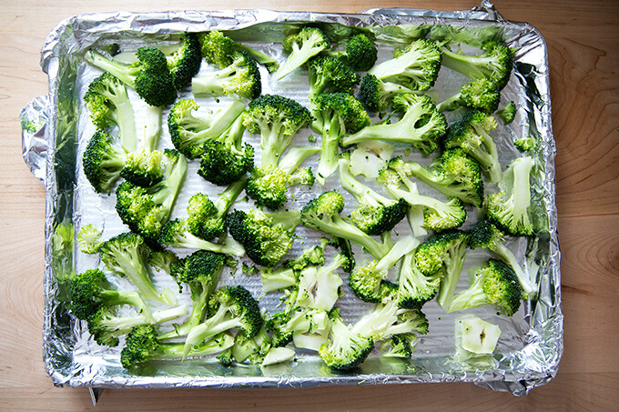 A sheet pan lined with foil topped with cut broccoli tossed with oil and salt.