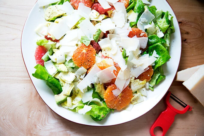 A platter topped with an endive, grapefruit and avocado salad, finished with shavings of parmesan.