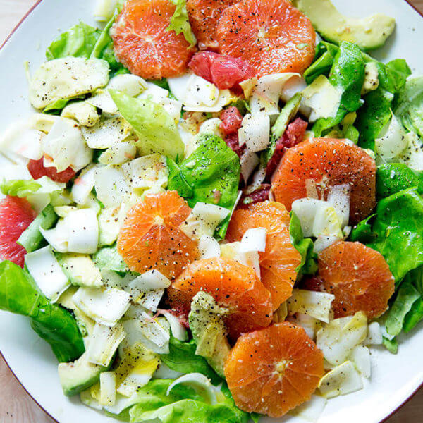 A platter topped with an endive, grapefruit and avocado salad.