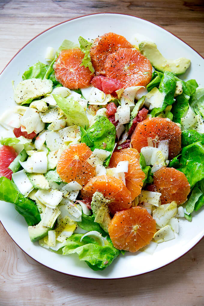 A platter topped with an endive, grapefruit and avocado salad.