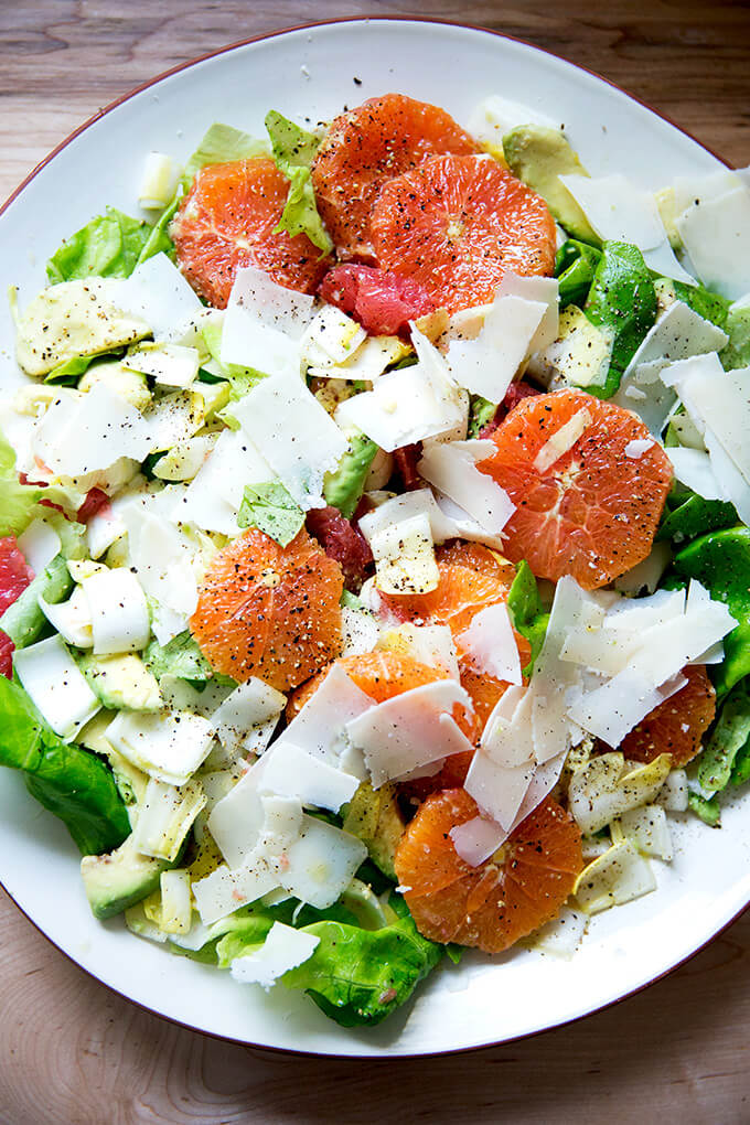 A platter topped with an endive, grapefruit and avocado salad, finished with shavings of parmesan.