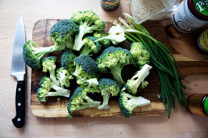 A board with chopped broccoli aside the condiments to make spicy broiled broccoli.