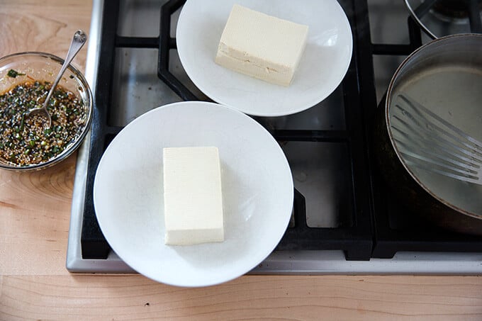 Two bowls each with a halved block of tofu inside.