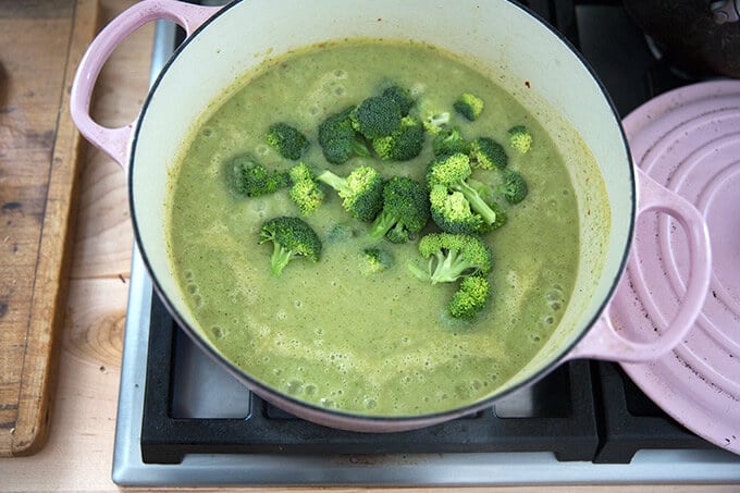 A Dutch oven with puréed broccoli-cheddar soup and fresh florets added on top.