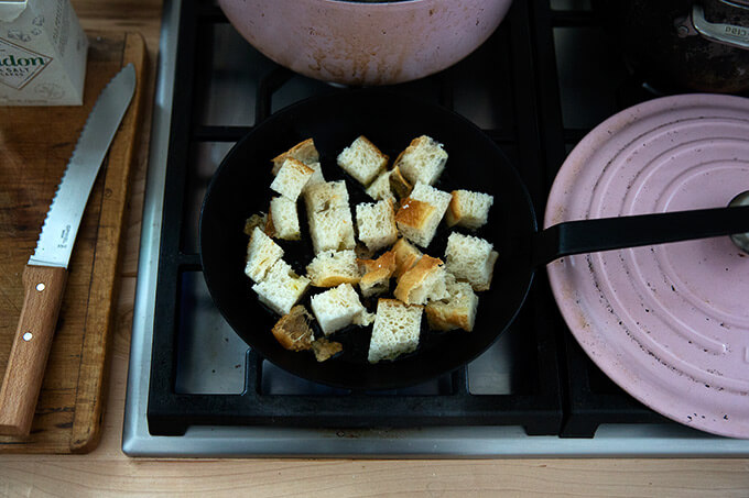 A skillet with cubed focaccia and olive oil.