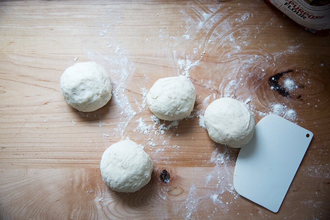 Four balls of naan dough balled up.