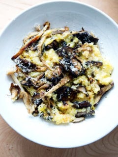 A bowl of roasted mushroom polenta bake topped with parmesan cheese and pepper.