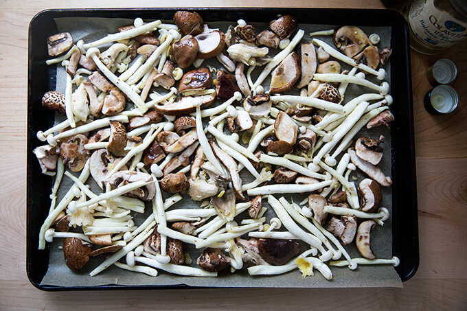 A sheet pan of mushrooms tossed with olive oil, vinegar, salt, and pepper.