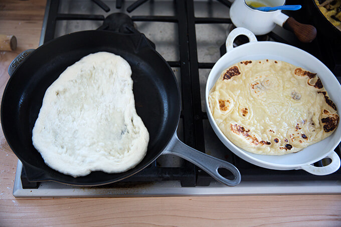 A skillet of naan aside freshly cooked naan.