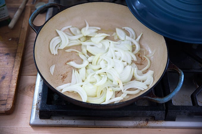 Onions sautéing stovetop in a skillet.