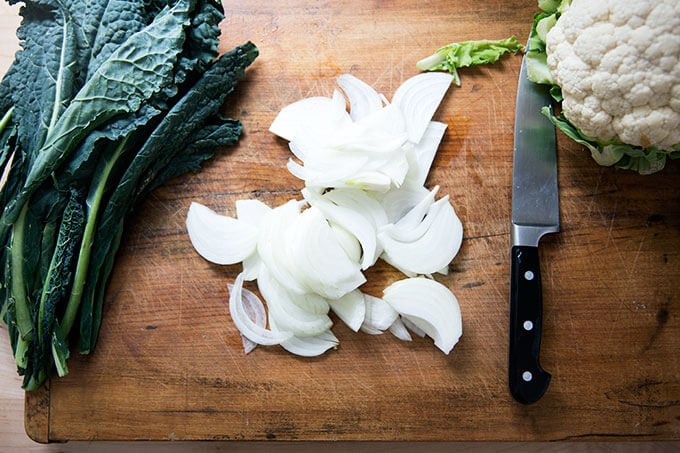 Kale, onions, and cauliflower on a board.