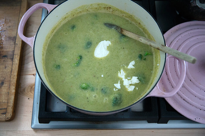 A Dutch oven with broccoli-cheddar soup and a dollop of Greek yogurt.