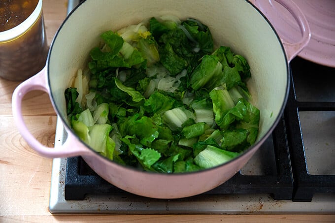 A Dutch oven filled with sautéed onions and wilted escarole.