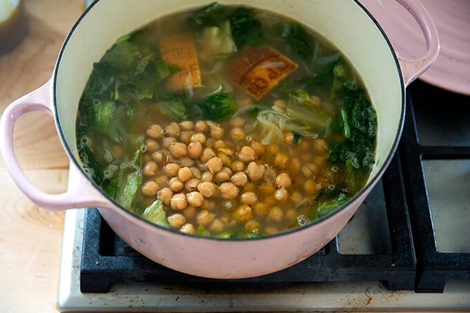 A Dutch oven filled with escarole and chickpea soup ready to simmer.