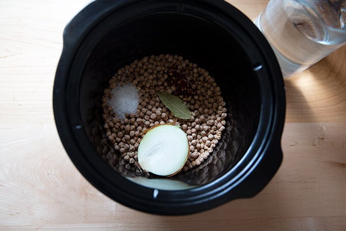 Overhead shot of a slow cooker with dried chickpeas and aromatics.