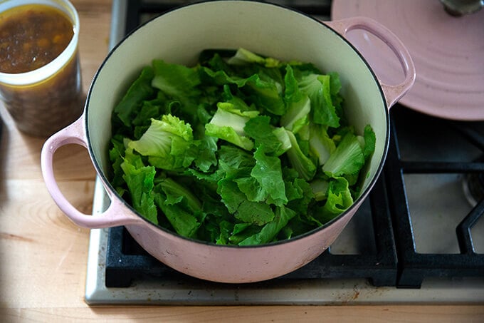 A Dutch oven filled with sautéed onions and escarole.