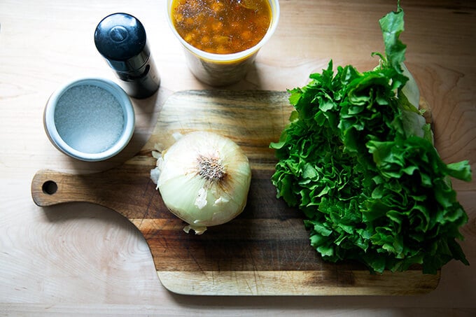 Ingredients to make escarole and chickpea soup on a board.