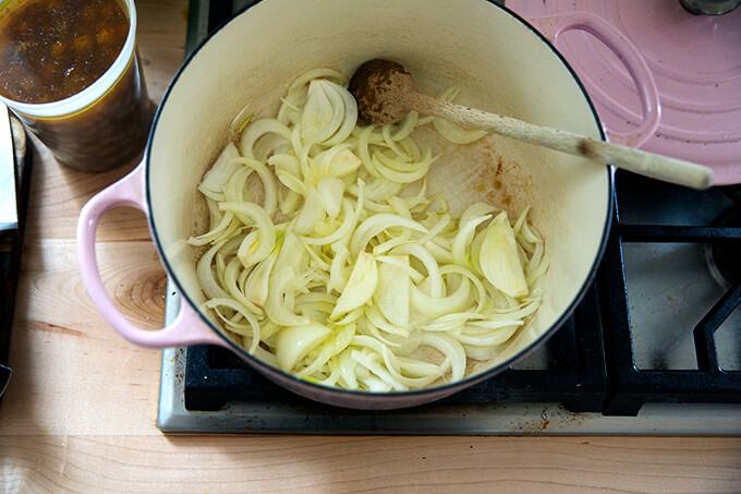 Sliced onions added to a Dutch oven stovetop.