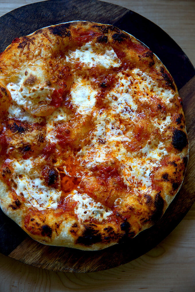 Just baked sourdough pizza crust topped with tomato sauce and mozzarella.