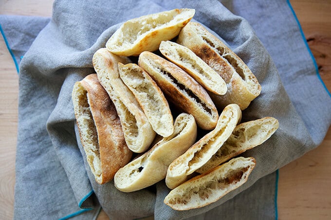 A bowl of cut open rounds of pita bread.