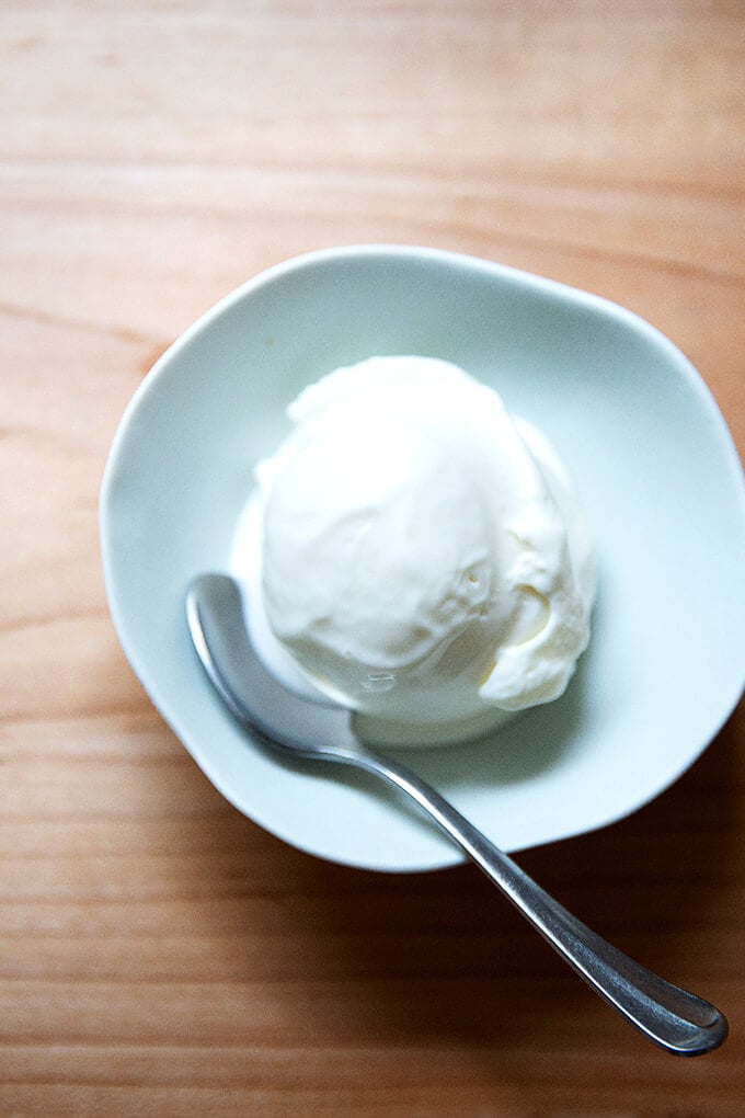 Homemade vanilla ice cream ball in spoon on ice cream container on