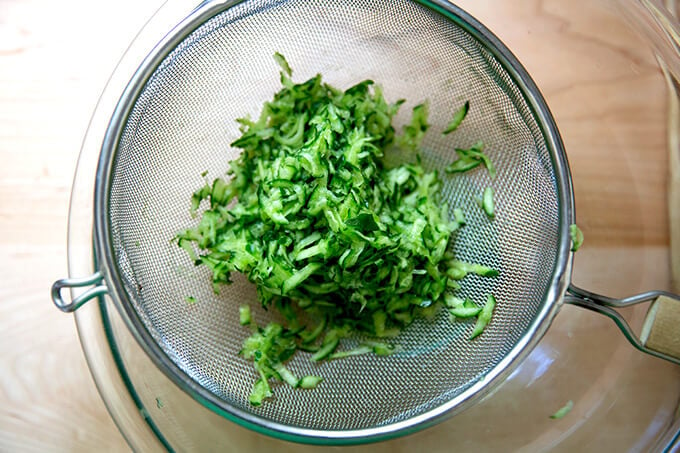 Grated cucumber drained in a sieve.