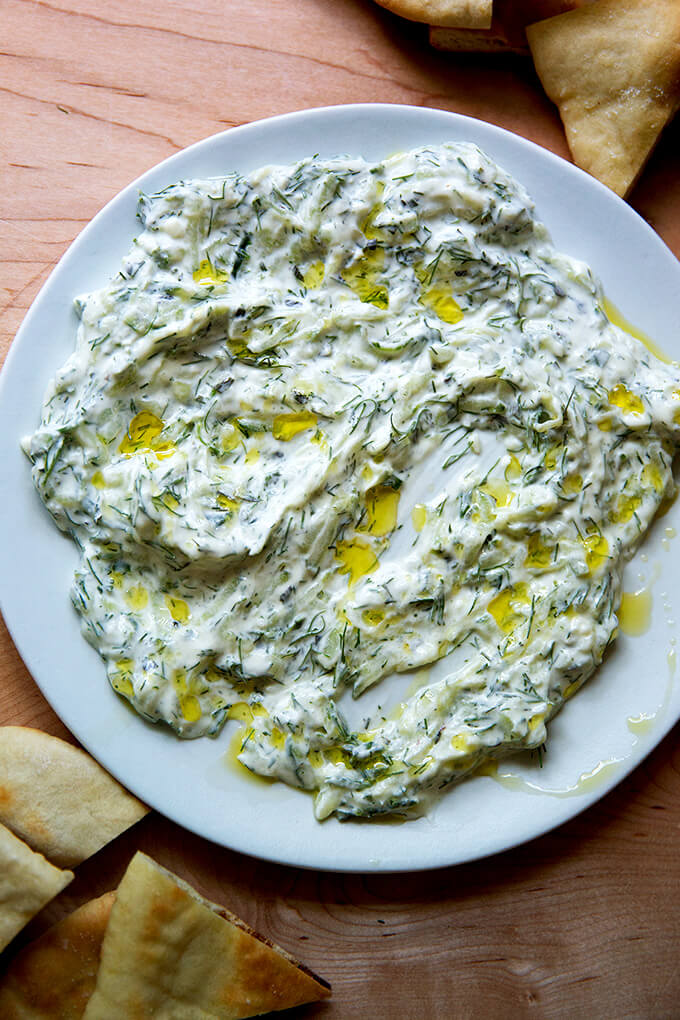 A platter of tzatziki, drizzled with olive oil aside pita.
