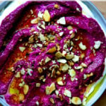 A platter of beet dip topped with toasted almonds.