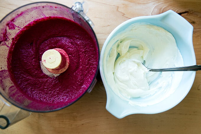 Components for the beet dip: raw puréed beet with seasonings aside a bowl of Greek yogurt seasoned with salt.