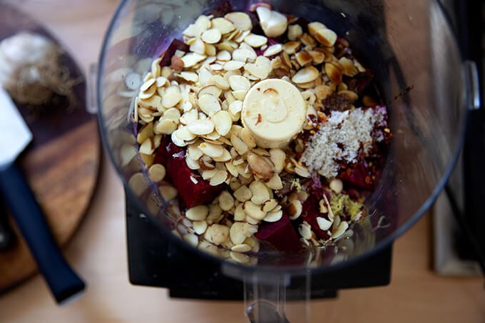 A food processor filled with the ingredients for a raw beet dip.