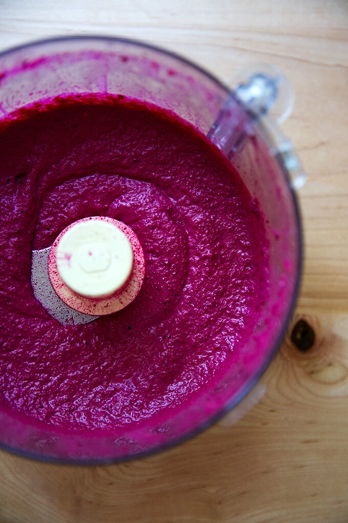 A food processor with puréed raw beet dip in it.