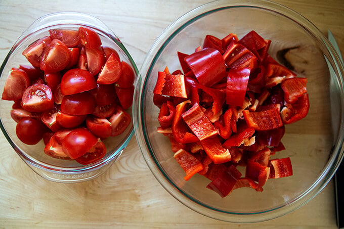 Two bowls of tomatoes and red bell peppers.