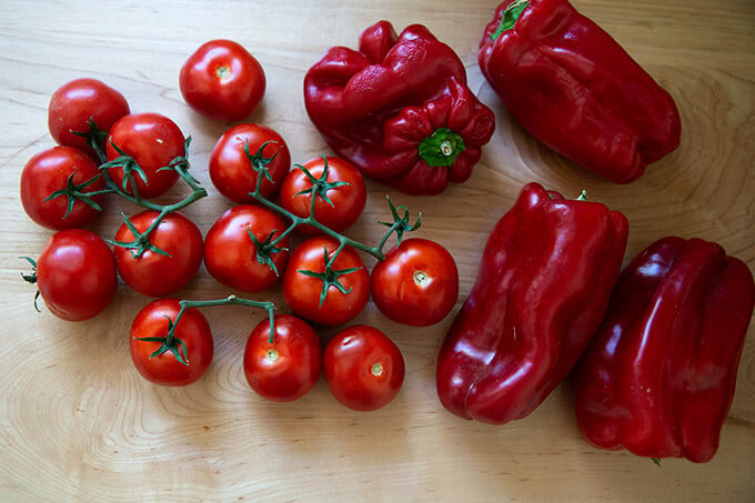 Tomatoes and peppers on a board.