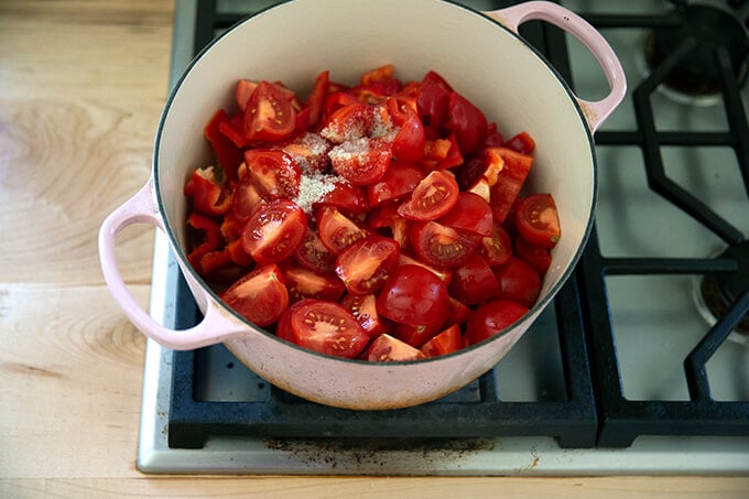 A large pot filled with tomatoes, peppers, water, and salt.