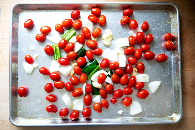 Tomatoes and roughly chopped onions, garlic, and jalapeño on a sheet pan.