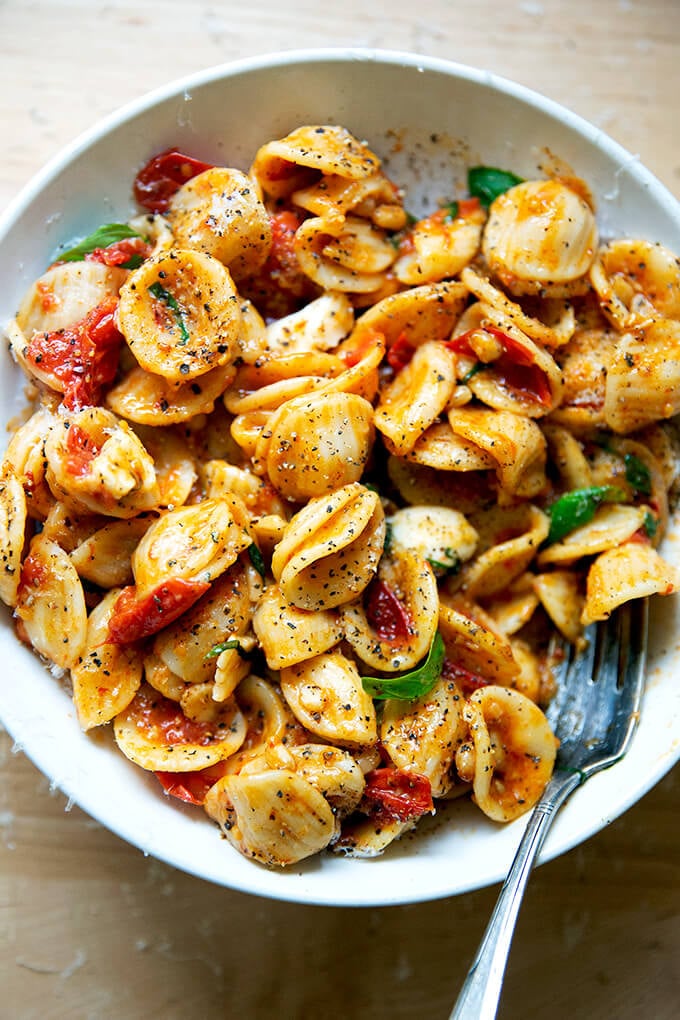 A bowl of pasta tossed with cherry tomato sauce, pine nuts, basil and mozzarella.