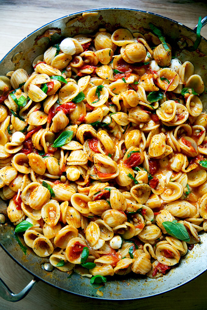 A skillet of pasta tossed with cherry tomato sauce, pine nuts, basil and mozzarella.