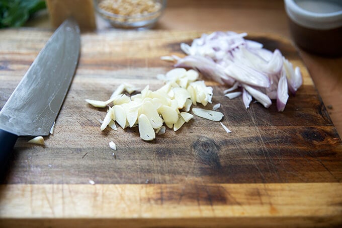 Thinly sliced garlic and shallots on a board.